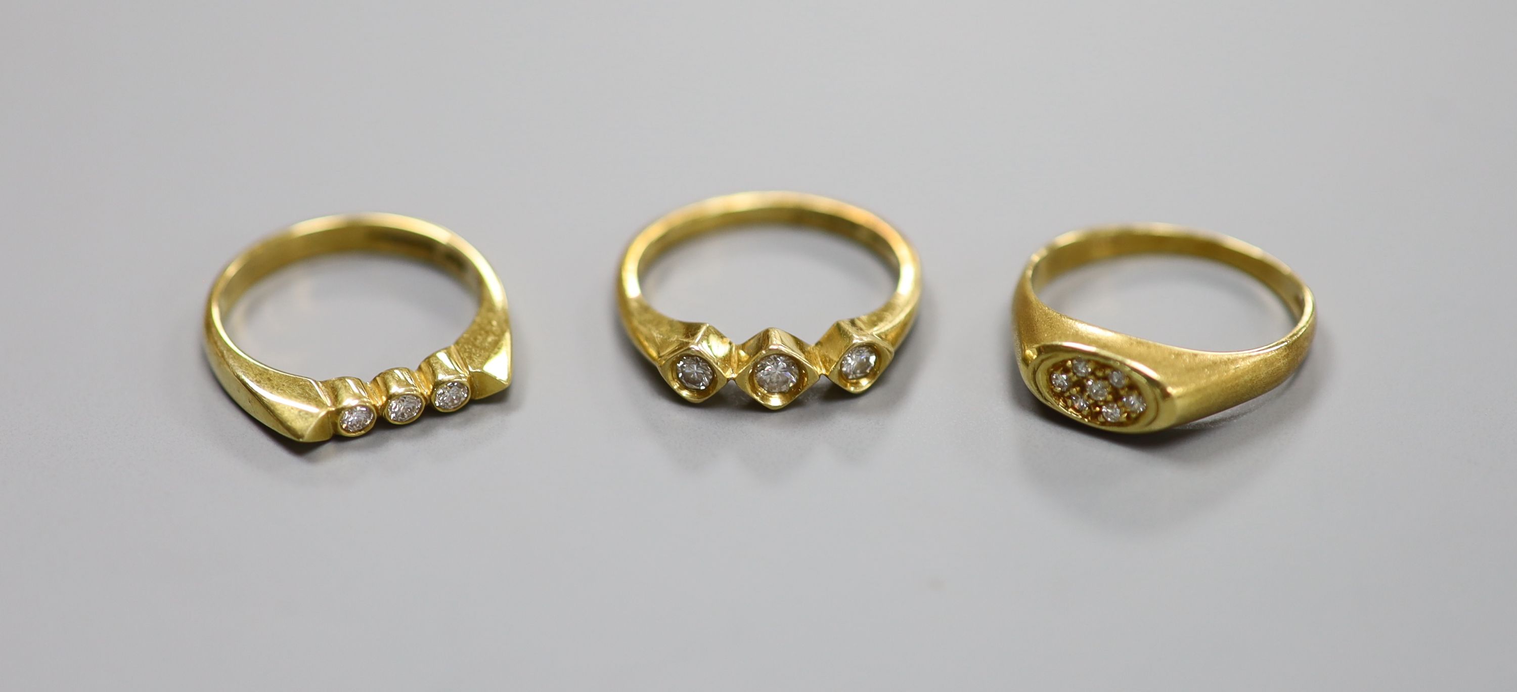 Three assorted modern 18ct gold and diamond set rings, including two three stones and a seven stone diamond chip cluster